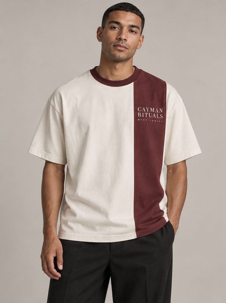 Studio render: a man in a bone T-shirt with a vertical oxblood panel and collar, the Cayman Rituals signature on the panel.